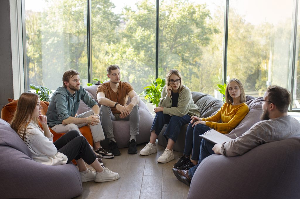 Groupe de jeunes échangeant avec un psychologue.
